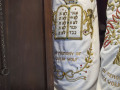 A close-up view of the left Torah scroll and a partial view of the middle Torah scroll on the left side of the ark.