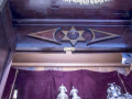 A close-up view of the woodwork on the inside top panel of the ark. The tops of the Torah coverings are partially visible at the bottom of the photograph.