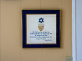 A close-up view of the framed, cross-stitched blessing hanging on the kitchen wall to the right of the stove.