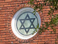 A close-up view of the round, Star of David stained glass window on the front of the synagogue.