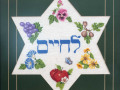 A close-up view of the framed needlepoint Star of David on the kitchen wall.
