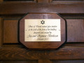 A close-up view of the plaque on the inside of the left, front door of the synagogue.