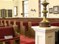 A view of the pews on the left side of the sanctuary. There are nine pews; each pew has a plaque on it except for the first pew. The first pew is partially visible on the far, right side of the photograph.