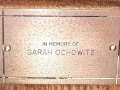 A close-up view of the plaque on the fifth pew from the front, on the right side of the sanctuary.