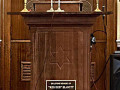 A close-up view of the pulpit and the plaque on the front of the pulpit. The Ark is partially visible behind the pulpit.