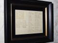 A close-up view of the framed signatures of the women who made the needlepoint tapestry.