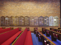 A view of the left wall of the sanctuary, showing the yahrzeit plaques, looking from right to left across the center of the sanctuary. There are several other yahrzeit plaques on this wall, to the right of the door.