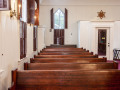 A view of the left side of the sanctuary, looking from the front of the sanctuary toward the back of the sanctuary. The inside door of the entry way is visible on the right side of the photograph.