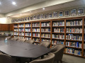 A view of The Stanley and Theodora Feldberg Jewish Resource Center (conference room/library), looking from the back, left corner of the room toward the right side of the room. The bookcase runs almost the entire length of the wall.