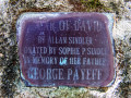 A close-up view of the memorial plaque mounted on the base of the double Star of David sculpture.