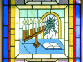 Menorah with the word “Remember” spelled out in the flames of the candles stained glass window, right side of sanctuary, 3rd window from the back.