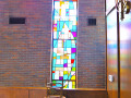 A view of the fourth, full length stained-glass window from the left, on the left wall of the sanctuary.