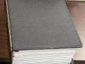 A view of the large, black binder, with information about the Holocaust and the Jews who perished in it, showing the thickness of the document.