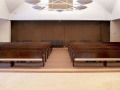 A view of the sanctuary, looking from the bema toward the back wall of the sanctuary. The alcove in the lobby is partially visible through the open door on the far, right side of the photograph.