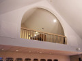 A close-up view of the organ loft on the left wall of the sanctuary. The yahrzeit plaques are partially visible on the wall below the loft.