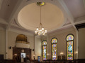 A partial view of the sanctuary showing the bema, ark, three of the four windows on the right wall of the sanctuary, and the ceiling and ceiling lights.