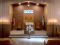 A close-up view of the front of the sanctuary, showing the two chairs, standing menorahs, and the standing floral arrangement in front of the bema. There is one chair next to each standing menorah.